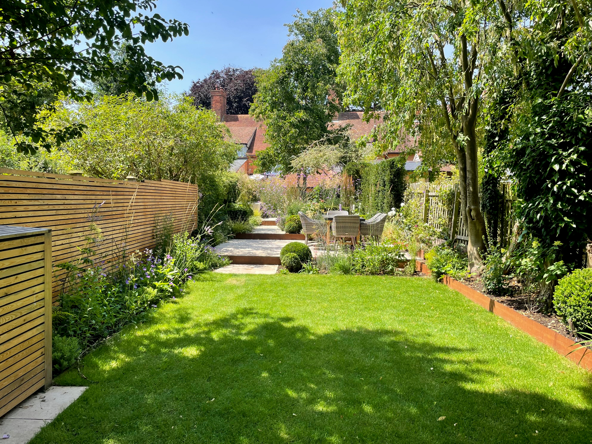 narrow urban rill garden with cor-ten steps and family lawn